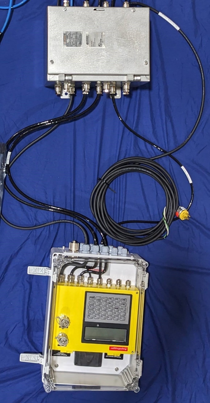 A yellow box with wires and a black cable

Description automatically generated
